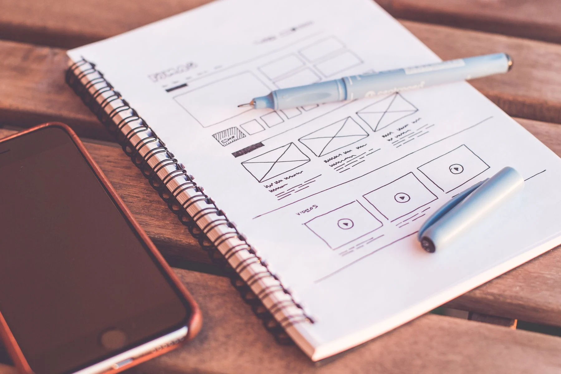 Website layout sketches in a notebook beside a phone